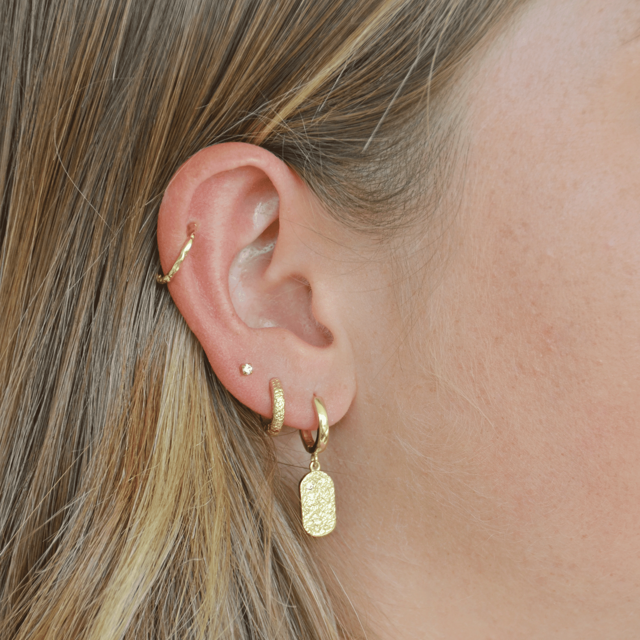 arms of eve mendoza gold huggie earrings on model close up of ear