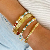 arms of eve gold cuff textured bracelet on model arm with stacked bangles